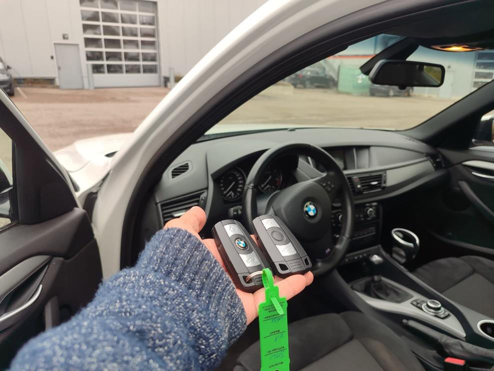 Two remote car keys held in a hand inside a vehicle