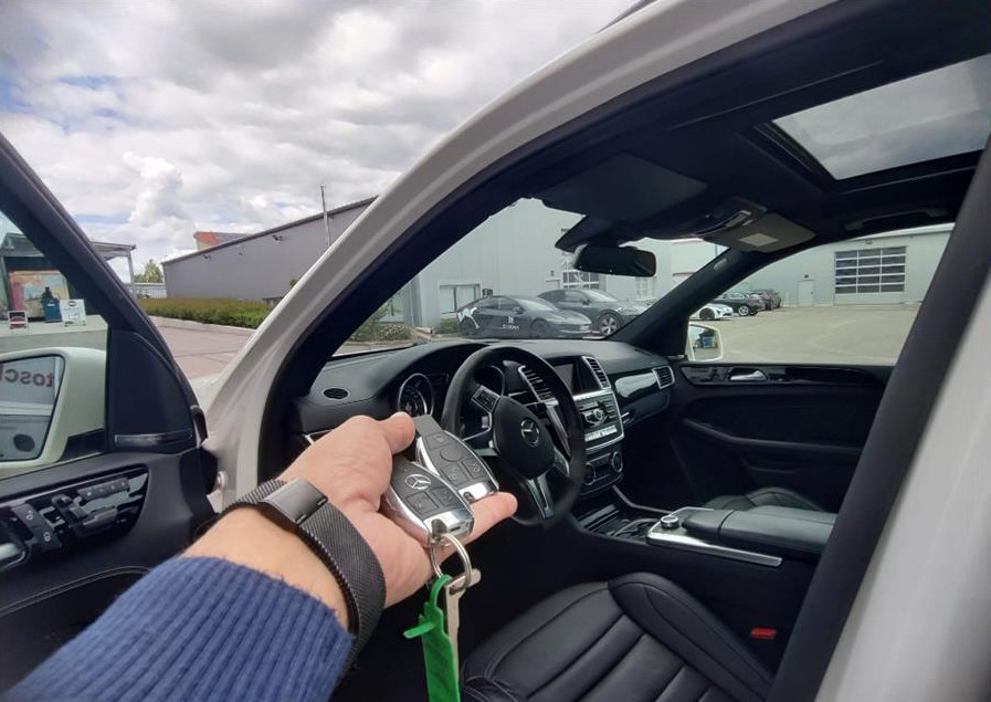Car key with remote held in a hand inside a vehicle